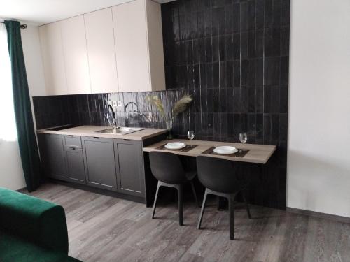 eine Küche mit einem Waschbecken und einem Tisch mit Stühlen in der Unterkunft Apartmán pri parku in Solčany