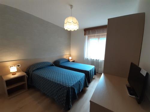 a hotel room with two beds and a window at Hotel Garnì Miramonti in Falcade
