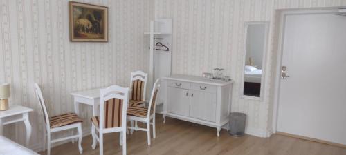 een witte kamer met een tafel en stoelen en een wastafel bij Liahof in Ullared