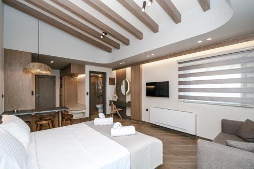 a bedroom with a white bed and a living room at Terra Hélios Suites & Studios in Kyparissia