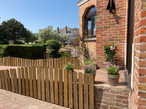 a wooden fence in front of a house with flowers at VILLA MICHRY Koksijde 4 adultes 2 enfants proche digue et centre in Koksijde