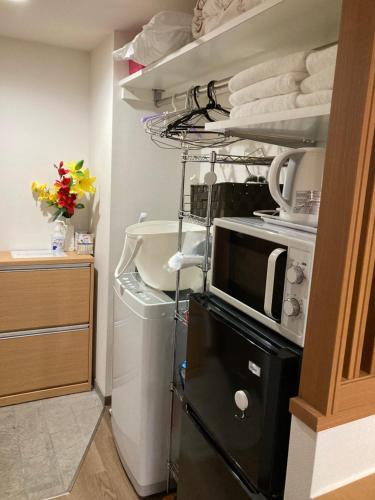 a kitchen with a microwave and a shelf with towels at 安ホテルサンシャイン in Tokyo