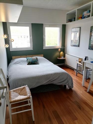 une chambre avec un grand lit et deux fenêtres dans l'établissement Aux arcades du lac, à Montigny-le-Bretonneux