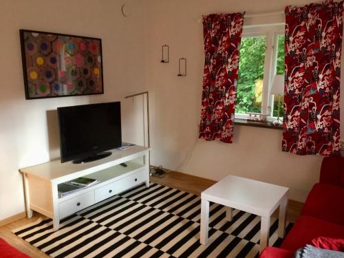 een woonkamer met een flatscreen-tv en een tafel bij Bäckalyckan in Röstånga