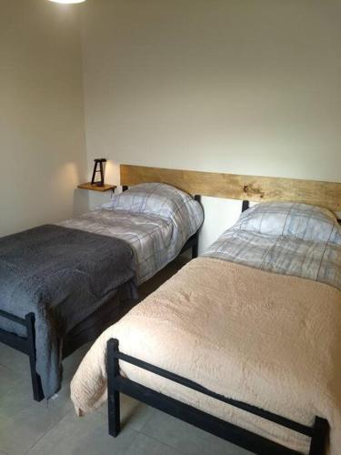 - une chambre avec 2 lits et une lampe sur le mur dans l'établissement departamento equipado Pioneros, à Zapala