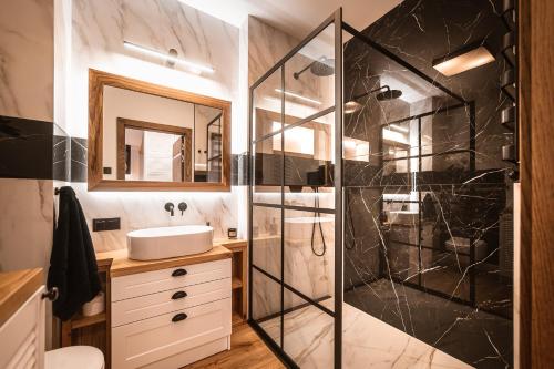 uma casa de banho com um chuveiro, um lavatório e um espelho. em Apartament Ukiel #23 I jezioro I prywatna plaża em Olsztyn