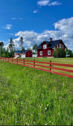 uma cerca vermelha em frente a uma casa vermelha em Litet hus på landet 