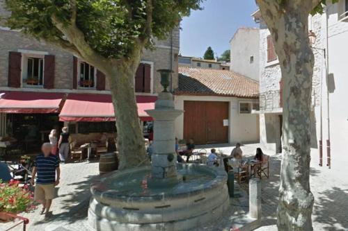 a fountain in a courtyard with people sitting at tables at Appartement cœur de village Numéro1 in Peyriac-de-Mer