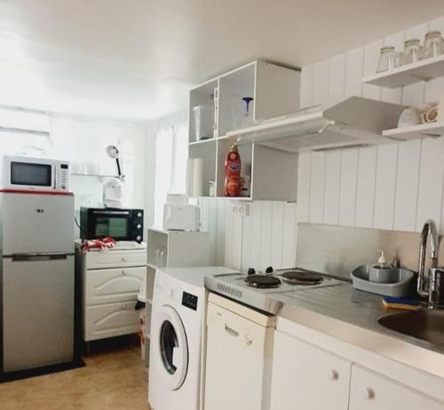 a kitchen with white cabinets and a washer and dryer at Charmant appartement 2p avec piscine partagée in La Ferté-Gaucher