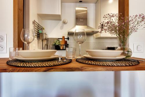 uma mesa com dois pratos brancos e taças de vinho em Appartement cosy, confortable et idéalement situé em Lyon