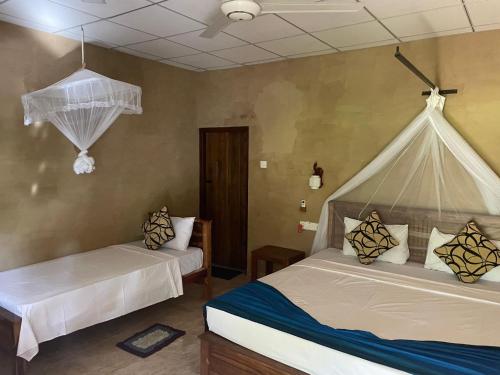 - une chambre avec 2 lits et des moustiquaires sur les murs dans l'établissement Shan Mango Homestay, à Sigirîya