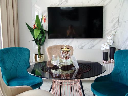 a living room with a glass table and blue chairs at Apartment LUXOR - Airport Katowice-Pyrzowice in Bobrowniki