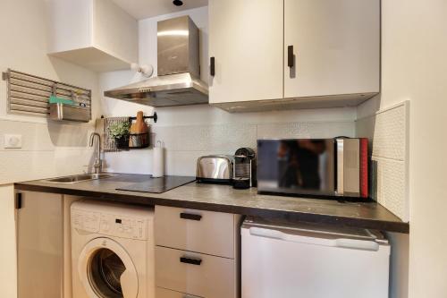 a kitchen with a microwave and a washer and dryer at Appartement cosy, confortable et idéalement situé in Lyon