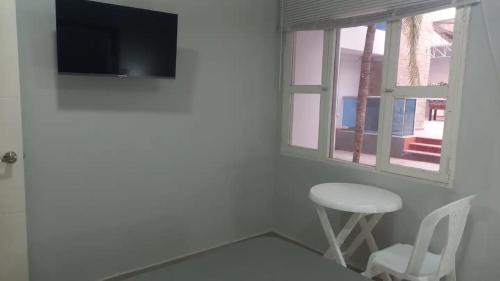a room with a tv and a stool and a window at Hotel BM-17 Cerca Al Mar Con Aire Acondicionada y Wifi in Cartagena de Indias