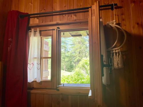 a window in a wooden room with a curtain at JARDIN DES ANGLAIS in Rhêmes-Notre-Dame