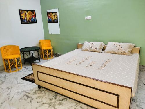 a bed in a room with two chairs and a bedvisor at Yellow Homestay - Modern 2BHK AC stay in Jabalpur