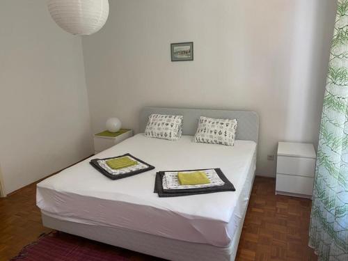 a small bedroom with a bed with two trays on it at Apartmani Dvojak Njivice in Njivice