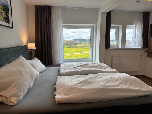 2 camas en una habitación con ventana grande en Zum Bayrischen Wirt, en Maierhöfen