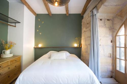 une chambre avec un lit blanc et un mur vert dans l'établissement Maison Bons Jours. Grange traditionelle avec piscine, à Perpezac-le-Blanc