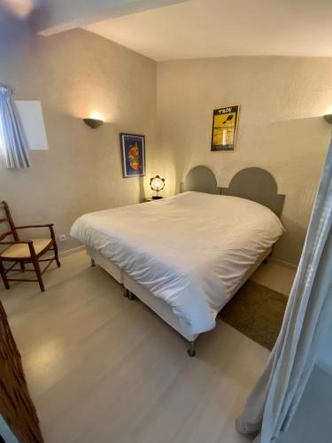 une chambre avec un grand lit blanc et une chaise dans l'établissement Studio sur les toits, à Villecroze