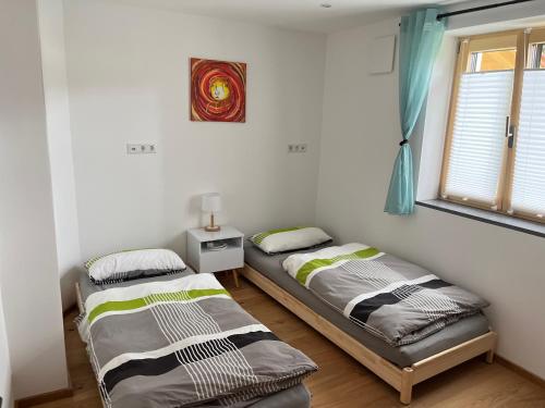 two beds in a room with a window at Ferienwohnung beim Mane in Schonstett