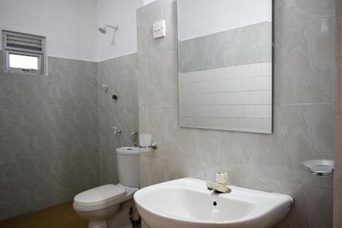 La salle de bains est pourvue d'un lavabo, de toilettes et d'un miroir. dans l'établissement Golden Beach Cottages, à Trincomalee