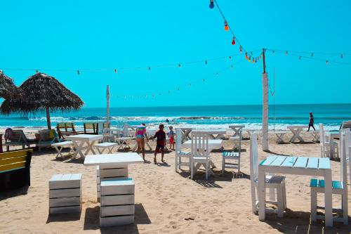 a beach with white chairs and tables and the ocean at Golden Beach Cottages in Trincomalee