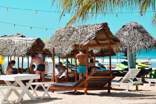 a group of people sitting on the beach under umbrellas at Golden Beach Cottages in Trincomalee