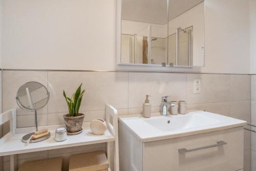 een witte badkamer met een wastafel en een spiegel bij Knusthof Lafrenz - Süd in Fehmarn