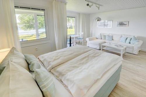 een slaapkamer met een groot bed en een woonkamer bij fewo1846 - Fjordview - komfortables Studioapartment mit Balkon und Meerblick in Glücksburg