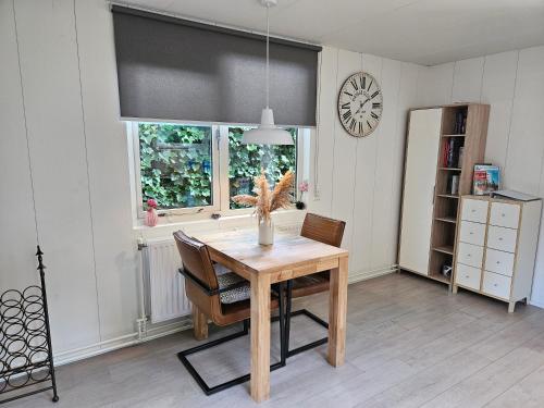 a dining room with a wooden table and a window at Zomerhuis Duinzicht in Egmond aan den Hoef