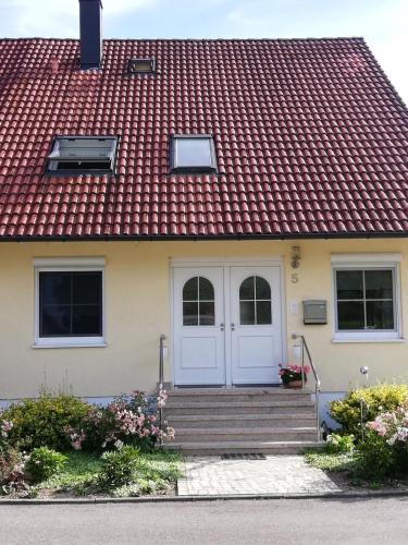 ユーバーリンゲンにあるFerienwohnung am Bodensee mit 3 Schlafzimmer über 2 Etage mit kleine Balkon bis 7 Personenの赤い屋根と白い扉の家