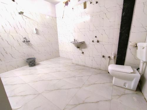 a white bathroom with a toilet and a sink at Yellow Homestay - Modern 2BHK AC stay in Jabalpur