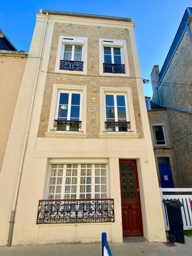 - un bâtiment avec une porte rouge et des fenêtres dans l'établissement Charming fisher house on the Seaside, à Grandcamp-Maisy
