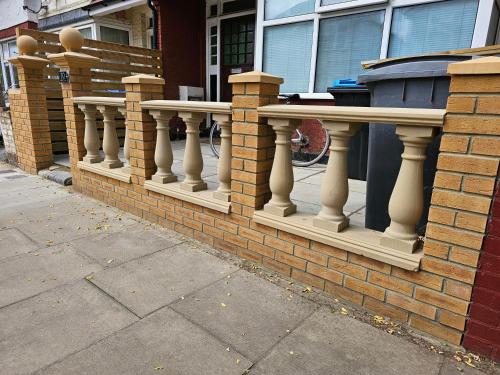 a brick fence with white pillars on a building at Lovely Rooms London in London
