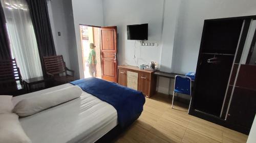 een slaapkamer met een bed, een bureau en een televisie bij OYO 92751 Marang Homestay Syariah 