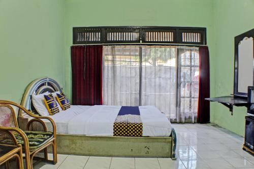 a bedroom with a bed in front of a window at SPOT ON 92682 Badar Guest House Syariah in Bandar Lampung