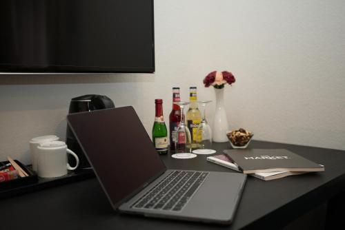 a laptop computer sitting on a desk with bottles of wine at Hotel Attaché an der Messe in Frankfurt/Main
