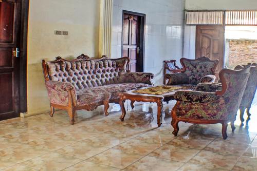 a living room with two couches and a table and chairs at SPOT ON 92682 Badar Guest House Syariah in Bandar Lampung