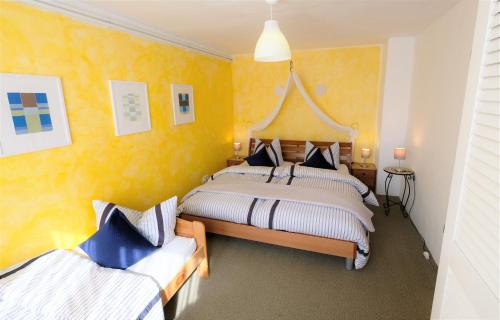 a bedroom with two beds with yellow walls at Ferienhaus 3 Zi im ART.Quartier in Velgast