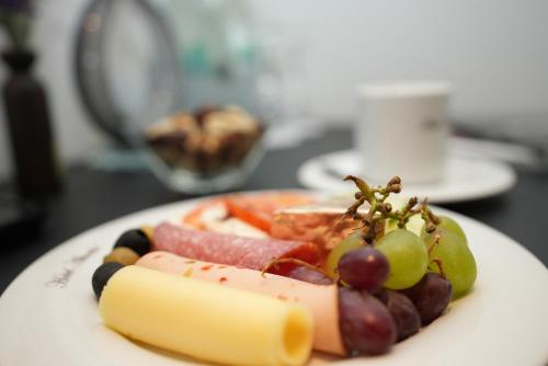 a plate of food with grapes and meat on a table at Hotel Attaché an der Messe in Frankfurt/Main