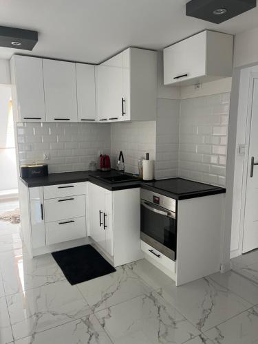 a white kitchen with white cabinets and black counter tops at Apartament Mazurski Sen in Giżycko