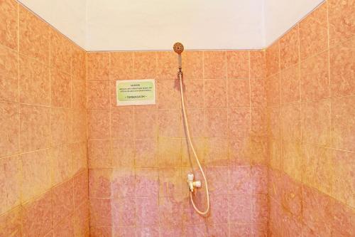 um chuveiro numa casa de banho em azulejo com uma placa na parede em OYO 92759 Penginapan Piji Kembar em Karanganyar