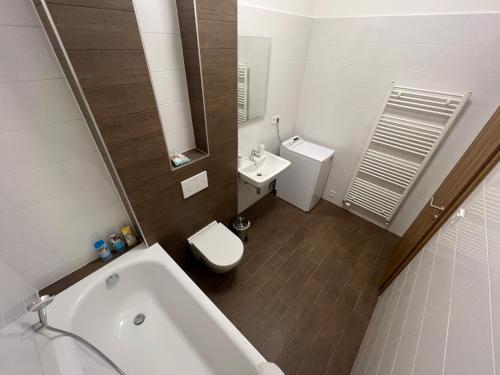 a bathroom with a tub and a toilet and a sink at Apartment YELLOW ROSE, Perfect Location with Free Parking, 24h Checkin & Balcony in Piešťany