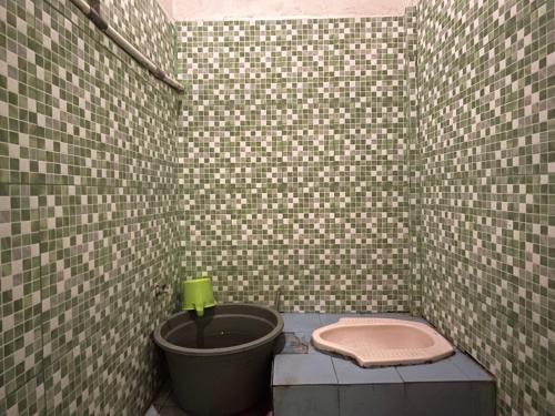 a small bathroom with a toilet in a tiled wall at SPOT ON 92766 Penginapan Asoka Indah in Barru