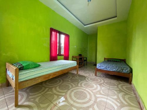 a green room with two beds and a window at SPOT ON 92766 Penginapan Asoka Indah in Barru