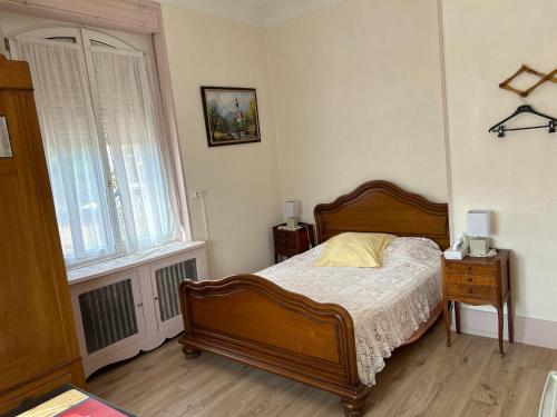 um quarto com uma cama de madeira e uma janela em Chambre Arnica lit 140 wifi sdb partagée em Saint-Amarin