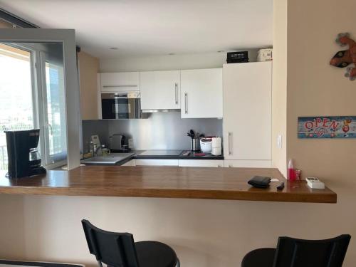 una cocina con armarios blancos y una barra con sillas en appartement cosy à 100m de la plage, CLIM, WIFI, piscine en Le Lavandou