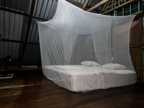 a bed covered in a net in a room at Beach house in Drake