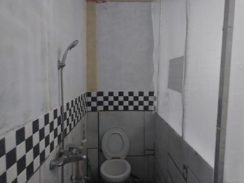 a bathroom with a toilet and a checkered wall at SPOT ON 92776 Panorama House in Tomohon
